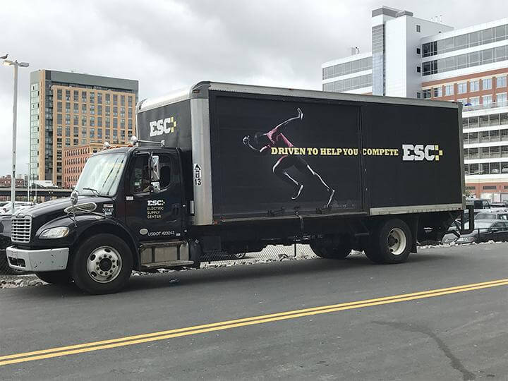 An ESC black truck with "driven to help you compete" on the side of the truck